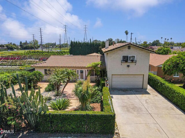 view of front of house with an attached garage, concrete driveway, stucco siding, and a chimney