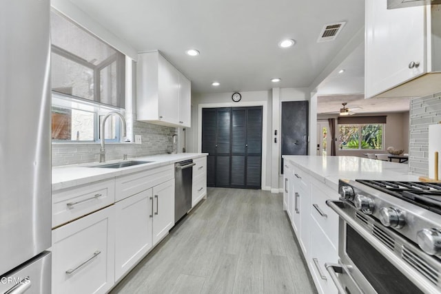 8534 Beverly Dr, San Gabriel, CA 91775 - kitchen featuring stainless steel appliances, tasteful backsplash, white cabinetry, light stone counters, and light wood-style flooring