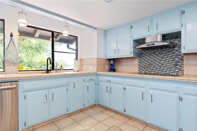 kitchen with blue cabinets, stainless steel dishwasher, and decorative backsplash