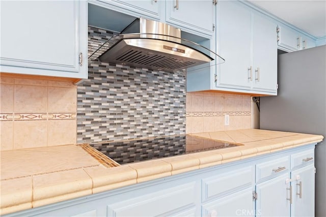 kitchen featuring extractor fan, backsplash, white cabinetry, and tile countertops