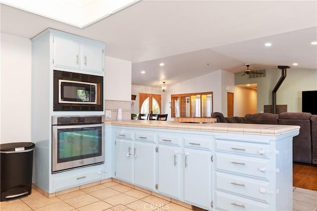 kitchen with oven, a peninsula, built in microwave, open floor plan, and lofted ceiling