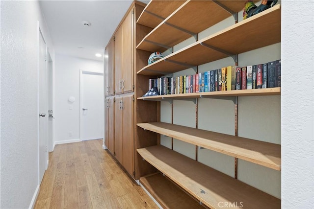 hallway with light wood-type flooring, baseboards, and recessed lighting