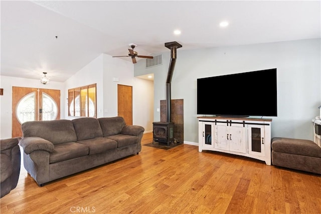 living area featuring vaulted ceiling, a wood stove, light wood-style flooring, a ceiling fan, and recessed lighting
