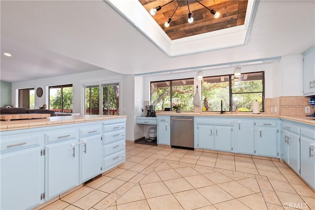 kitchen with dishwasher, light tile patterned floors, a sink, a raised ceiling, and wood ceiling