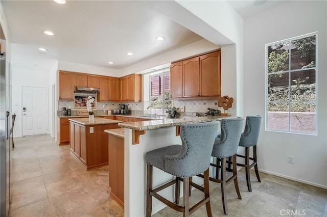 53 Via Palacio, San Clemente, CA 92673 - kitchen featuring a sink, backsplash, light stone countertops, a kitchen bar, and recessed lighting