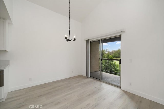 3180 Little Mountain Dr Unit D, San Bernardino, CA 92405 - unfurnished dining area with a chandelier, light wood finished floors, high vaulted ceiling, and baseboards