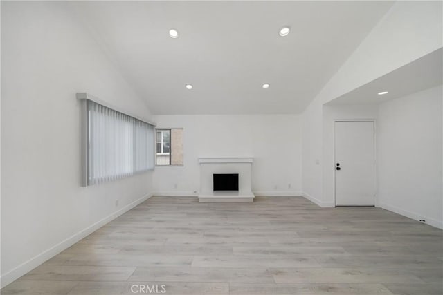 3180 Little Mountain Dr Unit D, San Bernardino, CA 92405 - unfurnished living room with lofted ceiling, recessed lighting, a fireplace with raised hearth, baseboards, and light wood-style flooring