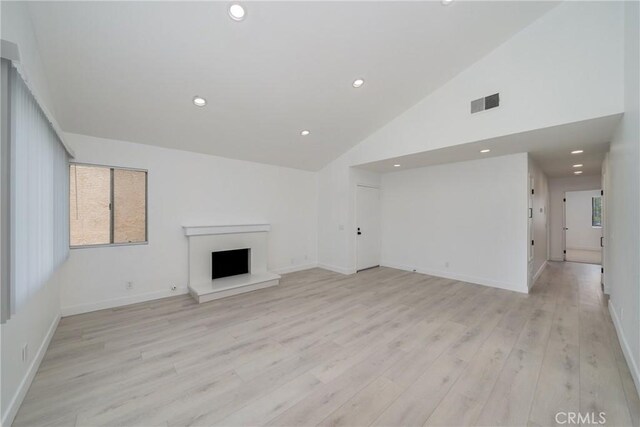 3180 Little Mountain Dr Unit D, San Bernardino, CA 92405 - unfurnished living room featuring light wood-style flooring, recessed lighting, a fireplace with raised hearth, baseboards, and high vaulted ceiling