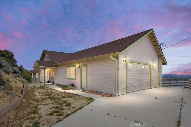 view of property exterior featuring concrete driveway, a garage, and fence