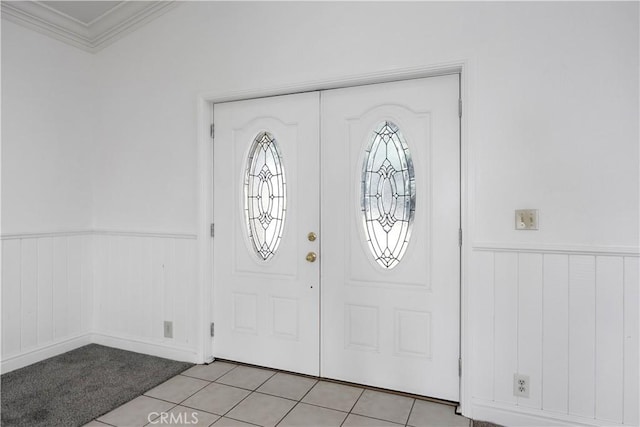 foyer entrance with wainscoting, crown molding, and light tile patterned floors
