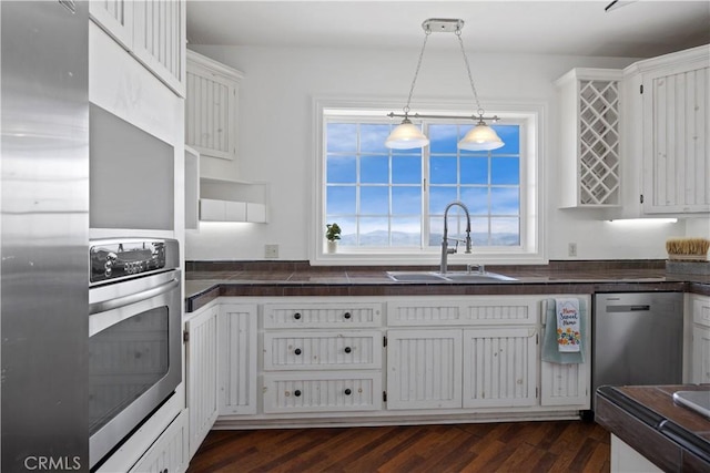 kitchen with stainless steel appliances, a sink, dark countertops, and healthy amount of natural light
