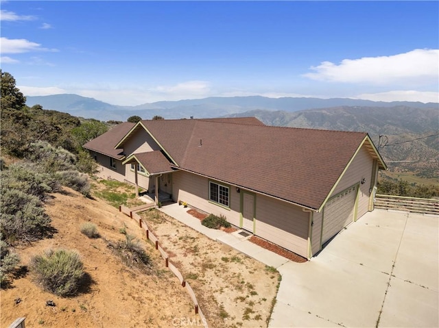 view of front of house featuring a mountain view, driveway, an attached garage, and fence