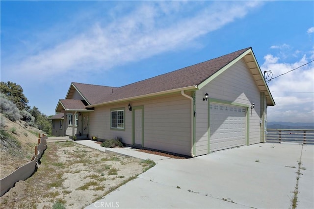 view of front of property with driveway, an attached garage, and fence