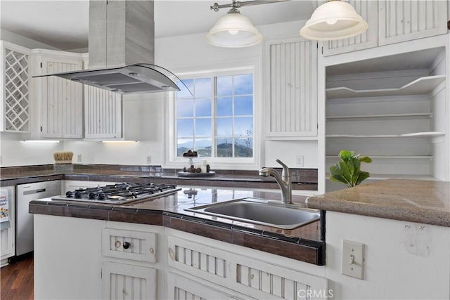 kitchen with island exhaust hood, a sink, appliances with stainless steel finishes, dark countertops, and hanging light fixtures