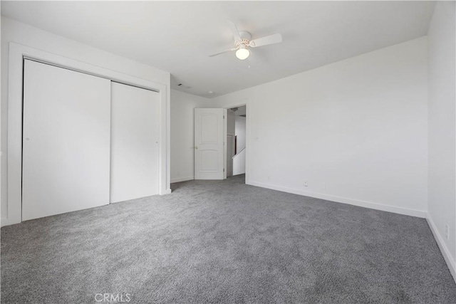unfurnished bedroom with carpet, a closet, a ceiling fan, and baseboards