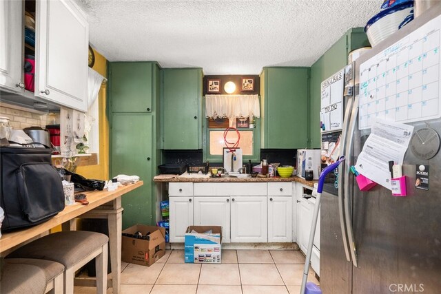 1825 Magnolia Ave, Chico, CA 95926 - kitchen with freestanding refrigerator, white cabinetry, light tile patterned floors, a textured ceiling, and tasteful backsplash