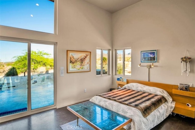 bedroom featuring a towering ceiling, access to exterior, and finished concrete flooring