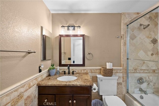 15 Vittoria St, Laguna Niguel, CA 92677 - bathroom featuring toilet, vanity, bath / shower combo with glass door, wainscoting, and tile walls
