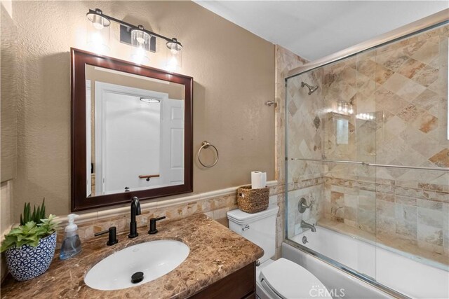 15 Vittoria St, Laguna Niguel, CA 92677 - bathroom with toilet, vanity, shower / bath combination with glass door, tile walls, and wainscoting
