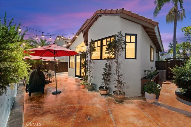 15 Vittoria St, Laguna Niguel, CA 92677 - back of house at dusk featuring stucco siding, a patio area, cooling unit, and outdoor dining area