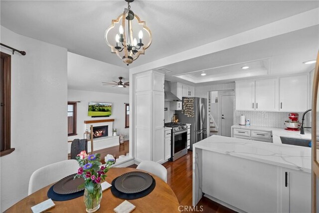 15 Vittoria St, Laguna Niguel, CA 92677 - kitchen featuring stainless steel appliances, a sink, a lit fireplace, wall chimney exhaust hood, and white cabinetry