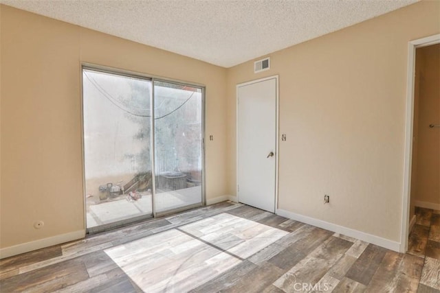 unfurnished bedroom with access to outside, wood finished floors, a textured ceiling, and baseboards