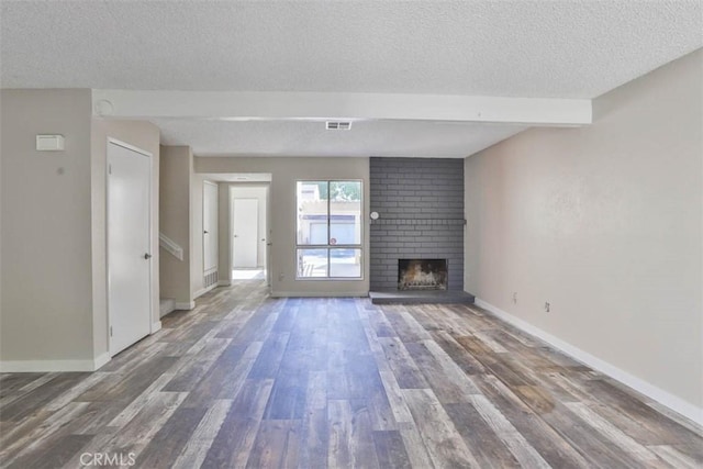 unfurnished living room featuring a textured ceiling, wood finished floors, a fireplace, baseboards, and beamed ceiling