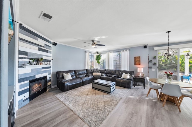 32871 Levi Ct, Temecula, CA 92592 - living area featuring wood finished floors, ceiling fan, a tiled fireplace, crown molding, and a chandelier