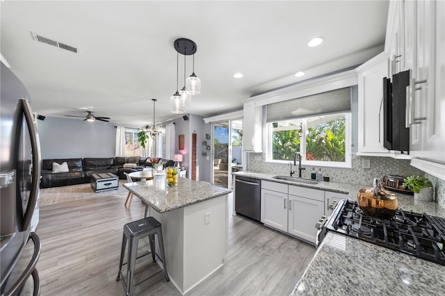 32871 Levi Ct, Temecula, CA 92592 - kitchen with appliances with stainless steel finishes, a kitchen island, tasteful backsplash, open floor plan, and white cabinets