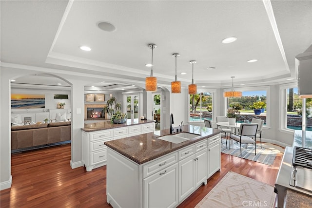 8 Capri, Laguna Niguel, CA 92677 - kitchen with arched walkways, a sink, a raised ceiling, an island with sink, and dark wood-style flooring