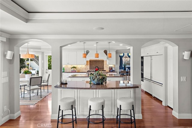 8 Capri, Laguna Niguel, CA 92677 - kitchen with a kitchen island with sink, a kitchen bar, tasteful backsplash, white cabinets, and crown molding
