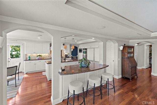 8 Capri, Laguna Niguel, CA 92677 - kitchen with arched walkways, dark wood-style flooring, white cabinetry, ornamental molding, and recessed lighting
