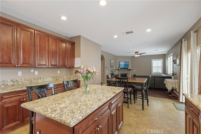 1709 Duncan Way, Corona, CA 92881 - kitchen with a ceiling fan, arched walkways, a center island, open floor plan, and light stone counters