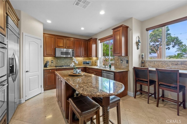 27781 Country Lane Rd, Laguna Niguel, CA 92677 - kitchen featuring a breakfast bar area, appliances with stainless steel finishes, a sink, light stone countertops, and backsplash