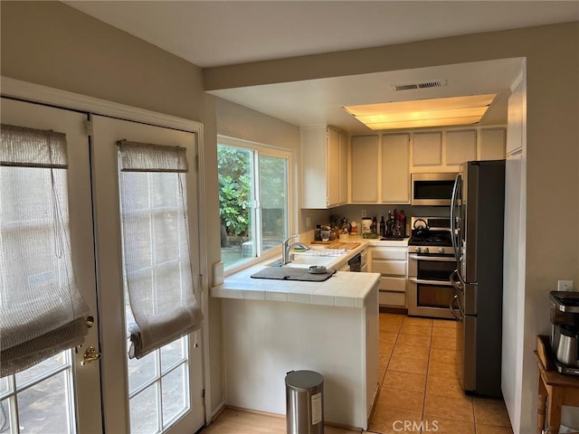 22523 Enadia Way, West Hills, CA 91307 - kitchen featuring tile counters, stainless steel appliances, light tile patterned floors, a sink, and white cabinetry