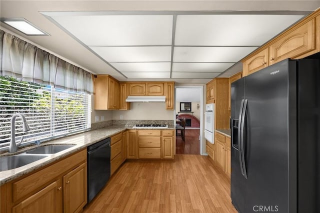 9906 Cedar Ct, Cypress, CA 90630 - kitchen featuring stainless steel fridge, a sink, black dishwasher, under cabinet range hood, and light wood-style flooring