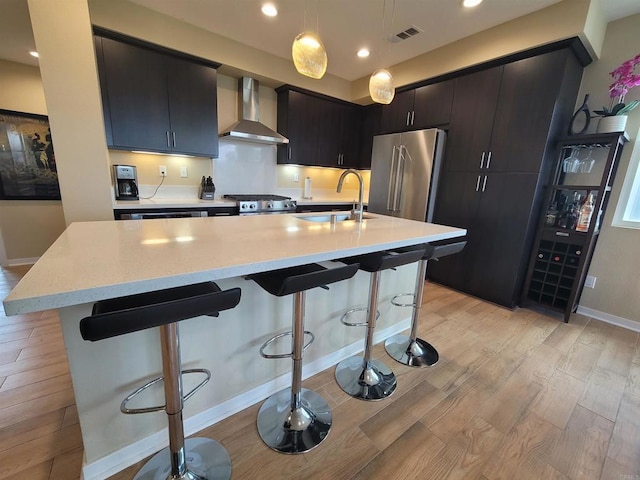 2072 Tango Loop Unit 2, Chula Vista, CA 91915 - kitchen featuring wall chimney range hood, stainless steel appliances, light wood-style floors, a kitchen breakfast bar, and pendant lighting