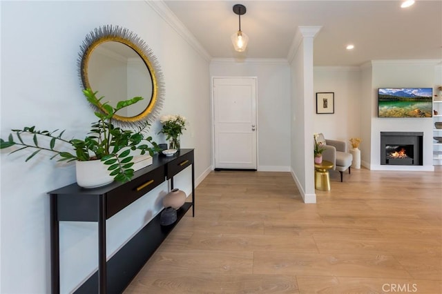 foyer entrance featuring ornamental molding, light wood-style flooring, recessed lighting, baseboards, and a warm lit fireplace