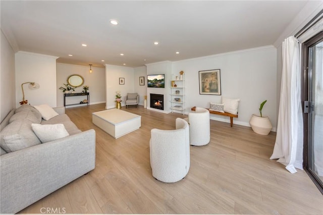 living area with crown molding, built in features, light wood finished floors, recessed lighting, and a lit fireplace