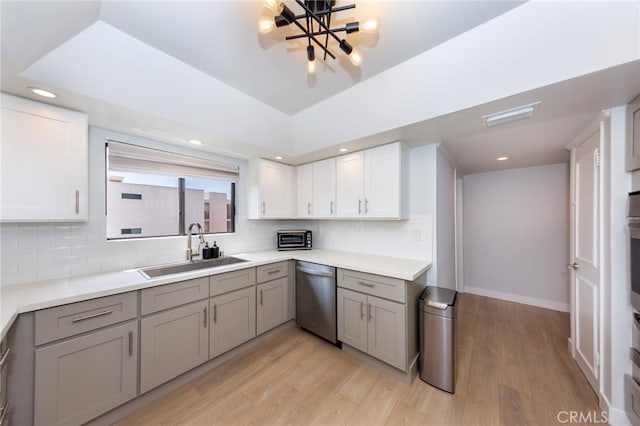kitchen with stainless steel dishwasher, a sink, gray cabinetry, light wood-style flooring, and recessed lighting