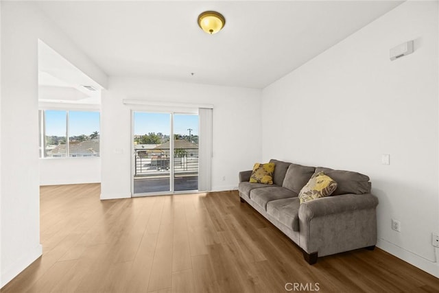 living area with healthy amount of natural light, wood finished floors, and baseboards