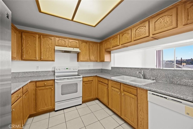 kitchen with white appliances, a sink, under cabinet range hood, light tile patterned floors, and brown cabinets