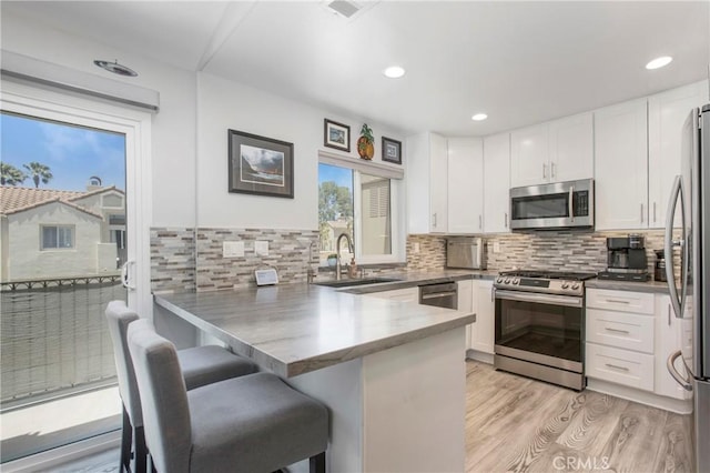 37 Fleurance St, Laguna Niguel, CA 92677 - kitchen featuring stainless steel appliances, a sink, a peninsula, white cabinets, and light wood-style floors