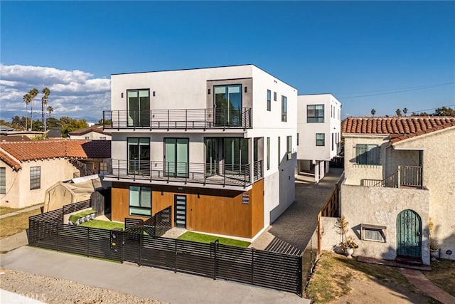 2202 Thurman Ave, Los Angeles, CA 90016 - modern home with a balcony, a fenced front yard, and stucco siding