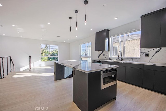 2202 Thurman Ave, Los Angeles, CA 90016 - kitchen featuring dark cabinetry, a kitchen island, a sink, light wood-style floors, and recessed lighting