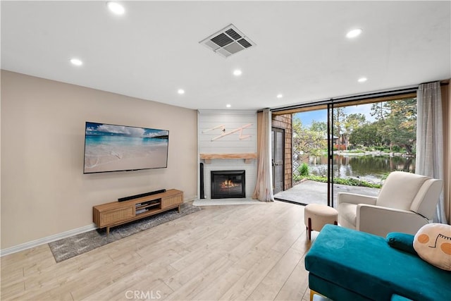 12750 Centralia St Unit 215, Lakewood, CA 90715 - living area featuring recessed lighting, light wood-style floors, floor to ceiling windows, a glass covered fireplace, and baseboards