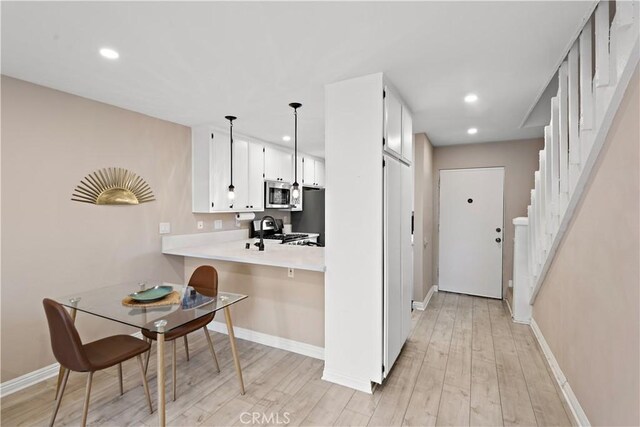 12750 Centralia St Unit 215, Lakewood, CA 90715 - kitchen featuring stainless steel appliances, light countertops, baseboards, light wood-style floors, and white cabinetry