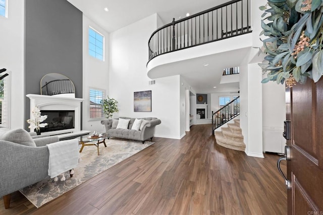 34056 Vandale Ct, Temecula, CA 92592 - living room with a glass covered fireplace, a high ceiling, wood finished floors, baseboards, and stairs