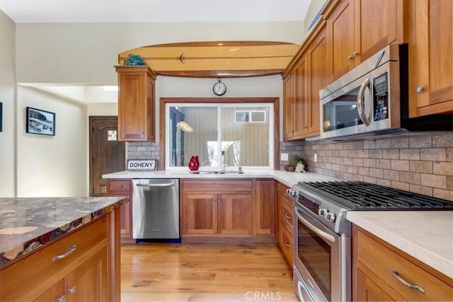 33441 N Spinnaker Dr N, Dana Point, CA 92629 - kitchen featuring appliances with stainless steel finishes, light wood-style floors, tasteful backsplash, and brown cabinets