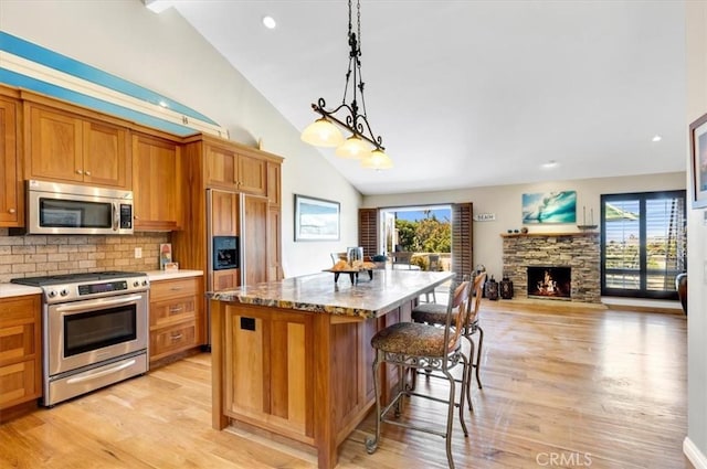 33441 N Spinnaker Dr N, Dana Point, CA 92629 - kitchen with appliances with stainless steel finishes, lofted ceiling, light wood-style flooring, a breakfast bar area, and brown cabinetry